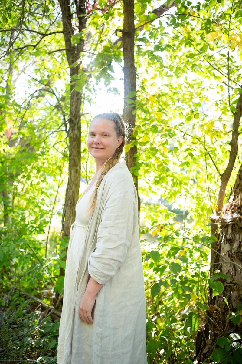 Tiina Kivinen among sunlit trees.
